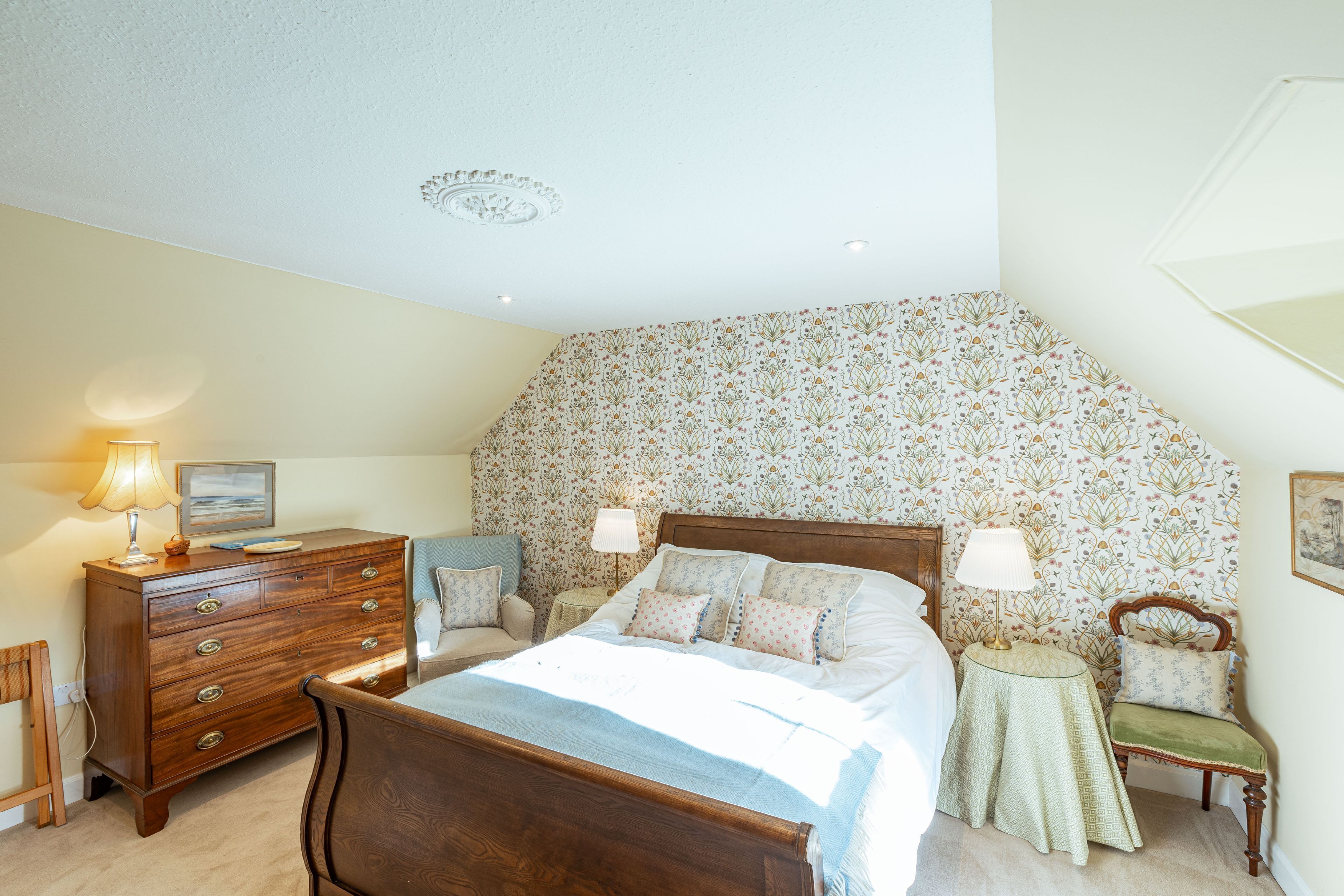 A bedroom with a wooden bed, a dresser, a nightstand, and a chair.