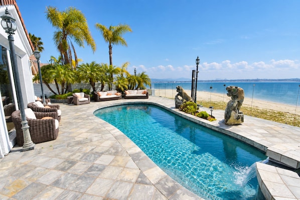 A swimming pool with a curved design, surrounded by lounge chairs and a stone deck.