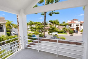 A balcony with a view of a residential street, palm trees, and houses. - Coronado Cays Beachfront with Private Pool & Spa (Coronado)