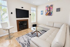 A modern living room with a flat-screen TV, a fireplace, a sofa, and a coffee table. - Coronado Cays Beachfront with Private Pool & Spa (Coronado)