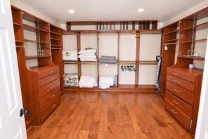 Ein begehbarer Kleiderschrank mit Holzböden, Schubladen und Kleiderstangen.