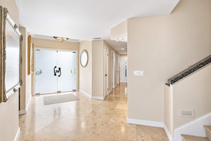 A hallway with a double door, a round mirror, and a staircase with a handrail. - Coronado Cays Beachfront with Private Pool & Spa (Coronado)