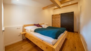 Ein Schlafzimmer mit einem hölzernen Bett, weißen Wänden und einer dunklen Holztür.