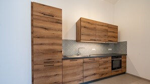 Eine Küche mit Holzausstattung, einem Einbauofen und einer gefliesten Spritzschutzwand.