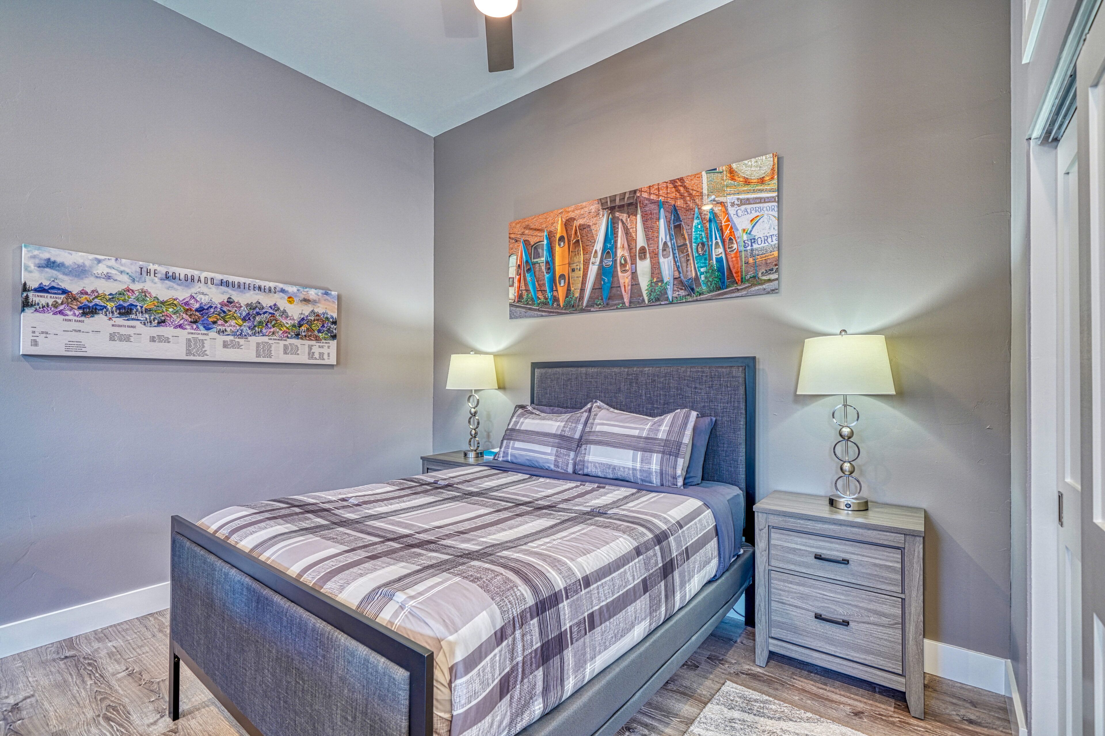 A bedroom with a bed, nightstands, and wall art.
