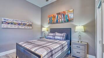 A bedroom with a bed, nightstands, and wall art.