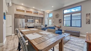A spacious kitchen with modern appliances, a dining area with a wooden table and chairs, and a large window providing natural light. - Salida Hideaway- New Studio Condo (Salida)