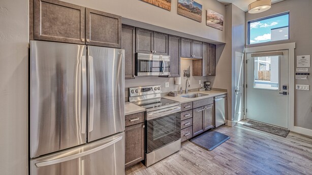 A modern kitchen with stainless steel appliances, wooden cabinets, and artwork on the walls. - Salida Hideaway- New Studio Condo (Salida)