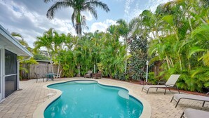 A backyard with a swimming pool, surrounded by palm trees and a wooden fence. - ‘Pelican Nest’, Tropical Naples Villa w/ Pool (Naples)