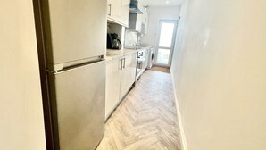 Una cucina moderna con mobili bianchi, forno integrato e pavimento con un motivo a spina di pesce.