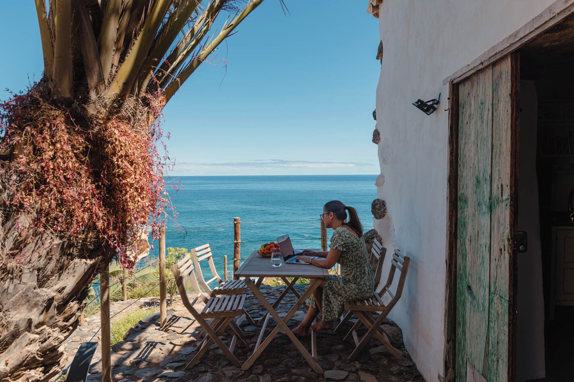 A coastal outdoor seating area with a table and chairs, overlooking the sea.