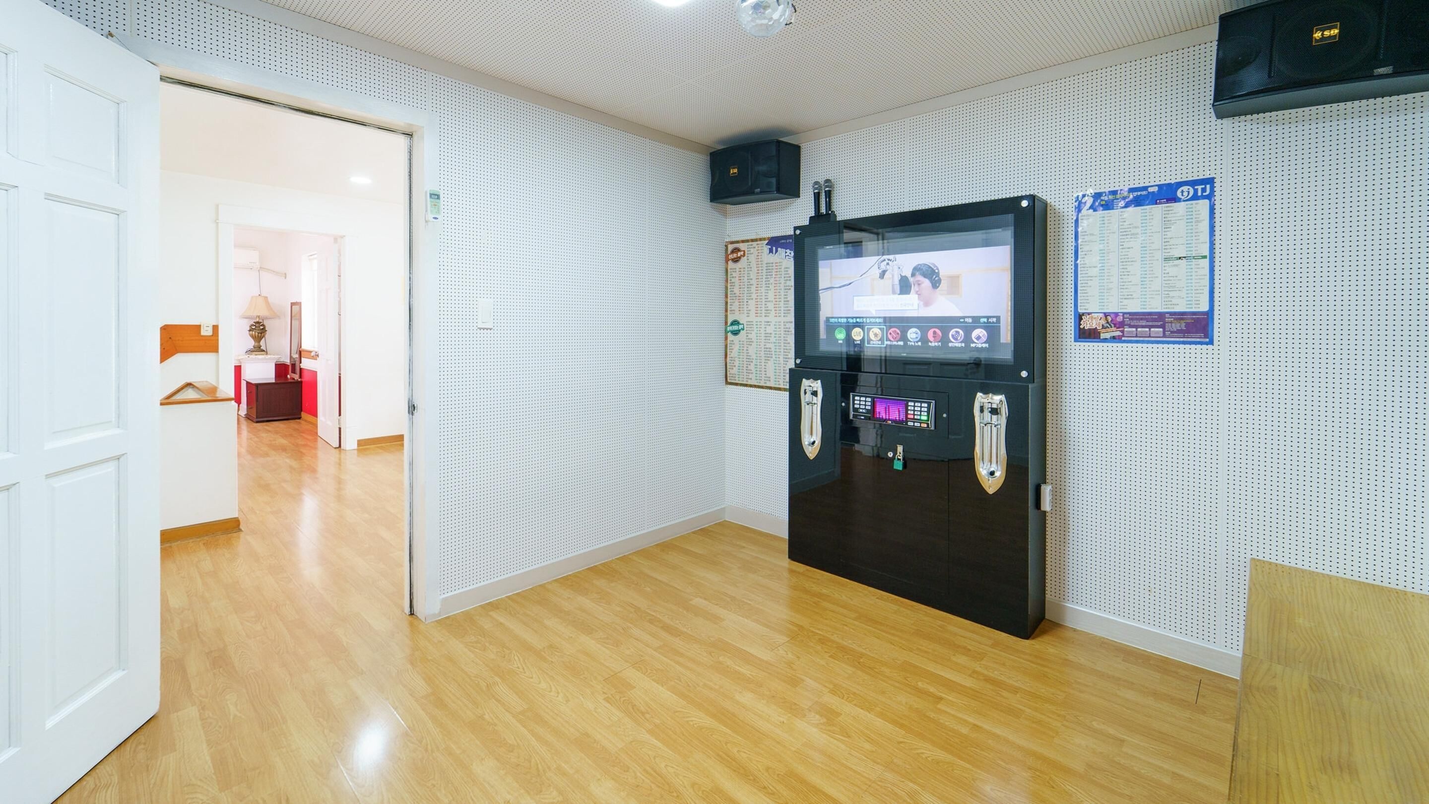 A modern room with a wooden floor, a black entertainment unit with a screen, and a pegboard wall.