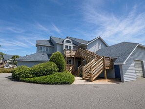 Una casa residencial con escalera de madera, garaje y césped cuidado.