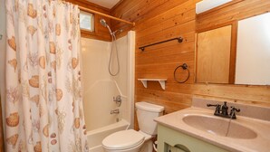 A bathroom with a wooden interior, a bathtub, a toilet, and a sink with a mirror above it. - The Last Resort ⛱️High on a dune with spectacular views - 4 BR/2 BA oceanside home in Duck⛱️ (Duck)