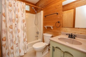 Een badkamer met houten inrichting, een bad, een toilet en een wastafel met spiegel.