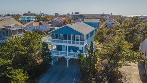 A coastal residential area with a prominent two-story house featuring a balcony and a covered porch. - The Last Resort ⛱️High on a dune with spectacular views - 4 BR/2 BA oceanside home in Duck⛱️ (Duck)