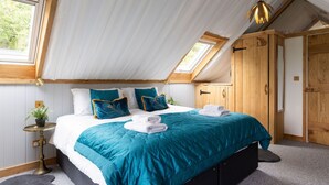 Ein Schlafzimmer mit einem großen Bett, einem kleinen Nachttisch, einer Topfpflanze und einem Kleiderschrank.