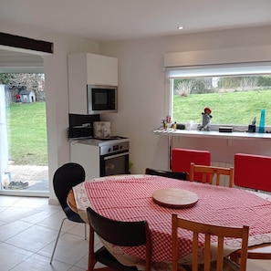 Una cocina compacta con microondas, horno y un pequeño comedor con mantel a cuadros.