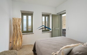 A bedroom with a bed, two windows, a door, and a view of the outdoors.