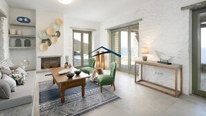 Un vaste salon doté d’une cheminée, d’un coin repas et offrant une vue sur la mer.