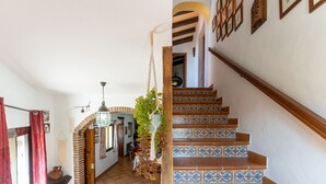 Un escalier recouvert de carreaux bleus et blancs, une plante suspendue et une main courante en bois.