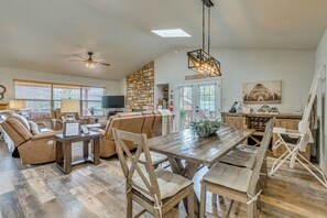 Un vaste espace de vie comprenant une table à manger en bois, des canapés en cuir et un mur décoratif en pierre.