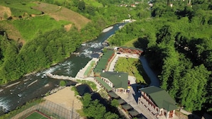 A riverside hotel with a long building, a swimming pool, and a tennis court. - Teona Caglayan Bungalov (Findikli)