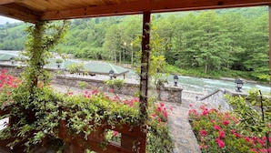A wooden pergola with a view of a river and lush greenery. - Teona Caglayan Bungalov (Findikli)