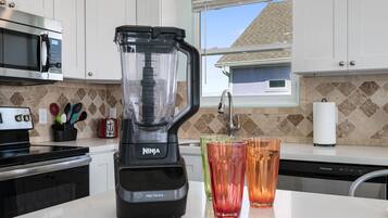 A kitchen with a Ninja Pro Touch blender, a toaster, and a window with a view of a house.