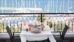 Une table dressée pour le petit-déjeuner, avec vue sur la mer et les bateaux.