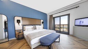 Une chambre d’hôtel moderne dotée d’un grand lit, d’une banquette, d’une télévision et offrant une vue sur le balcon.