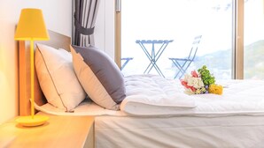 A neatly made bed with white bedding, a bedside lamp, and a bouquet of flowers. - Ganghwa Nolang Pension (Incheon)