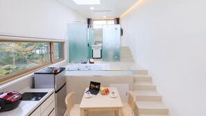 A modern kitchen with a dining area, a staircase, and a view of the outdoors. - Ganghwa Nolang Pension (Incheon)