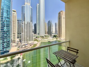 Un balcon offrant une vue sur des immeubles modernes et des étendues d’eau.