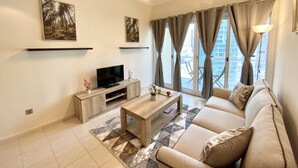 A modern living room with a flat-screen TV, a wooden coffee table, a beige sofa, and a patterned rug. - LKV - 1bed with 2 balconies in JLT (Dubai)
