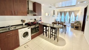A modern kitchen with a central island, built-in appliances, and a dining area with a view. - LKV - 1bed with 2 balconies in JLT (Dubai)