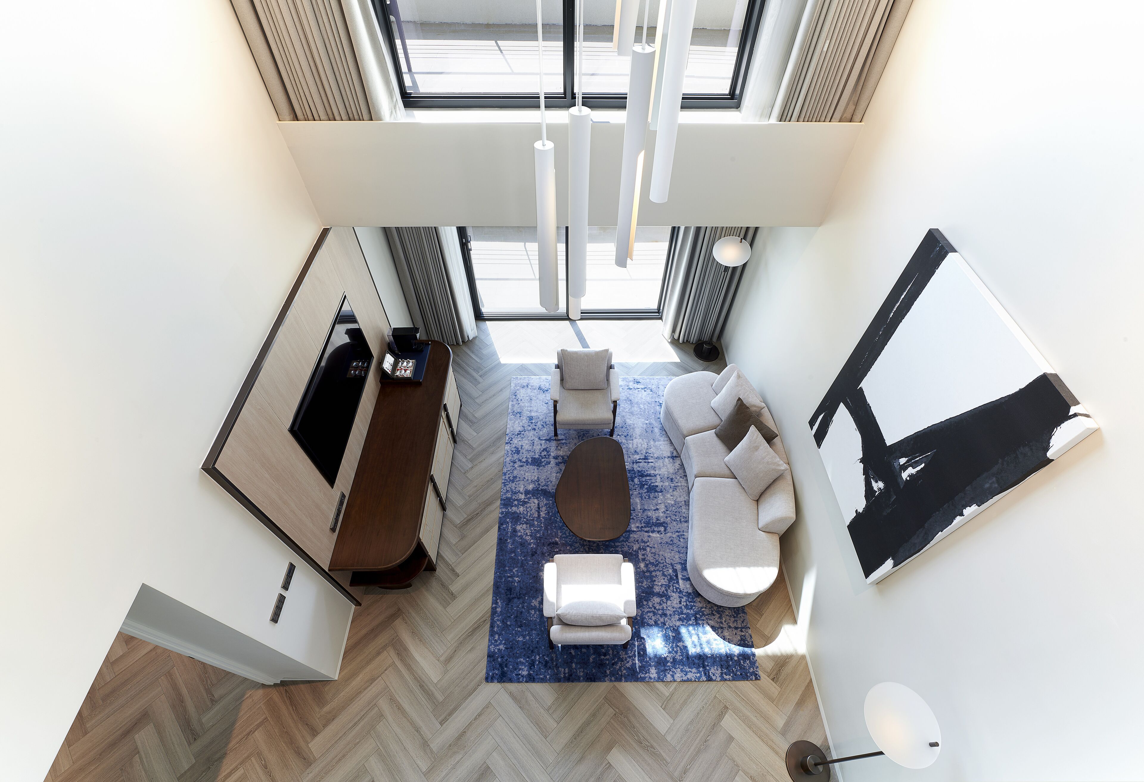 A modern hotel room with a large window, a sofa, a coffee table, and a painting on the wall.