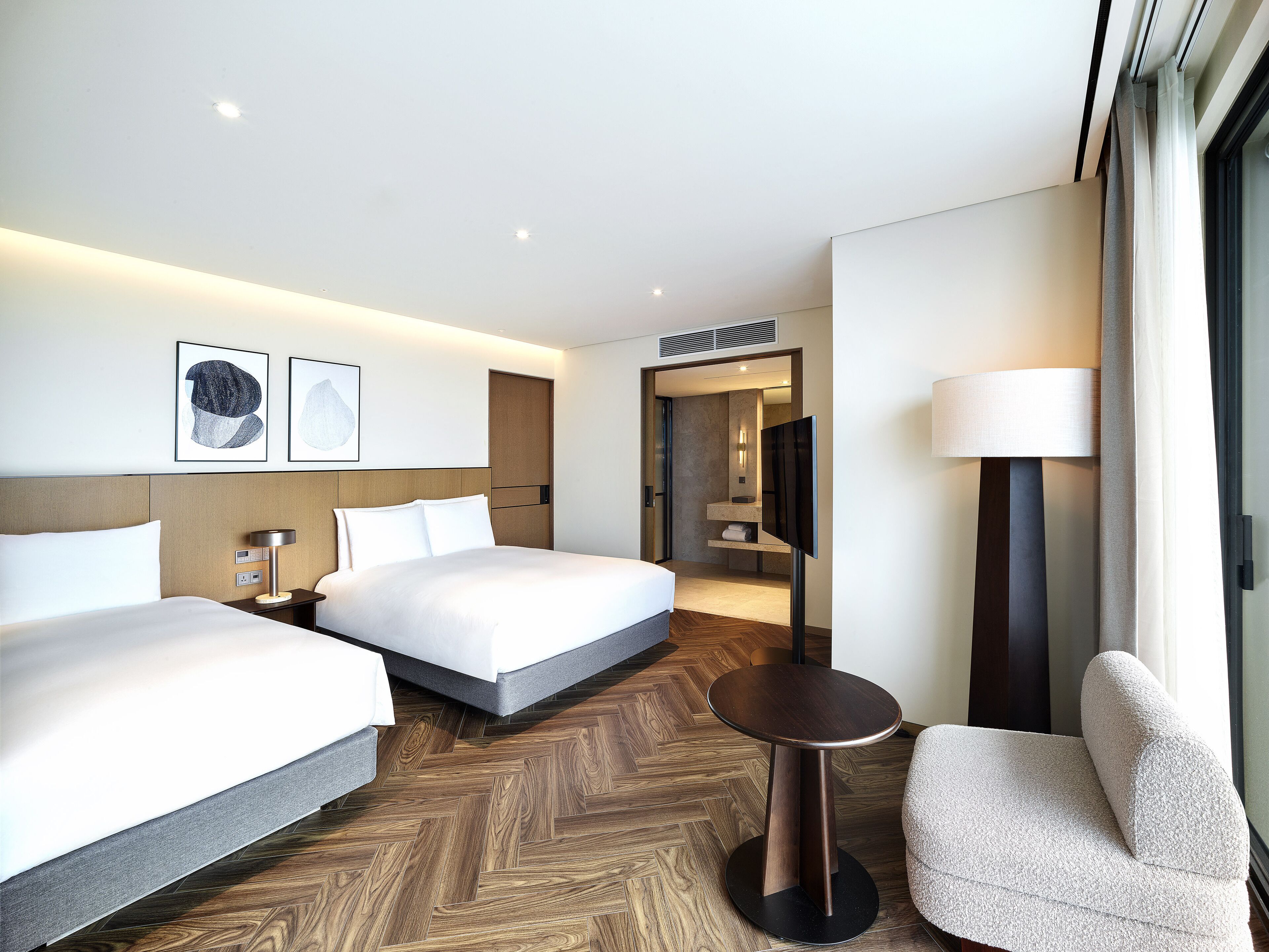 A hotel room with two beds, a TV, a desk, and a chair.