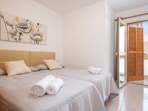 Ein Schlafzimmer mit Bett, Kissen, einem Gemälde und Blick durch eine Glastür.