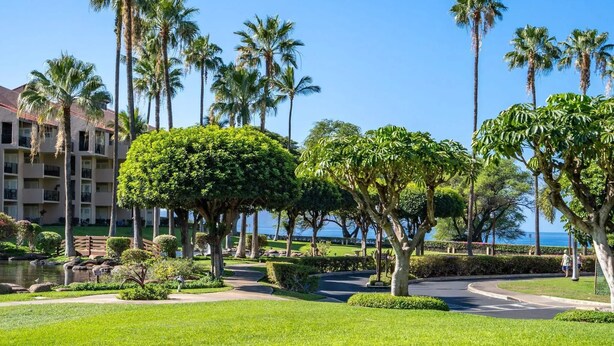 A resort with a well-maintained garden, palm trees, and a view of the ocean. - Maui Paradise: Steps to Sand-Blg#1. Partial Ocean View, AC's, Wifi, 1st Floor (Kihei)