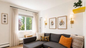 A modern living room with a grey sectional sofa, a small wooden coffee table, and a window with curtains.