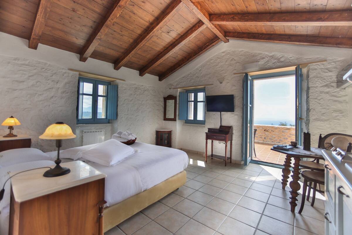 A bedroom with a bed, bedside lamps, a television, and a view of the outside.
