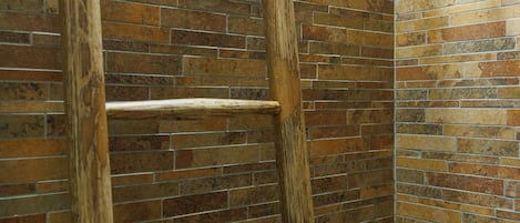 Une échelle en bois appuyée contre un mur de briques, dans un coin.