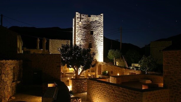 Un edificio de piedra con una torre, iluminado con una luz cálida durante la noche.