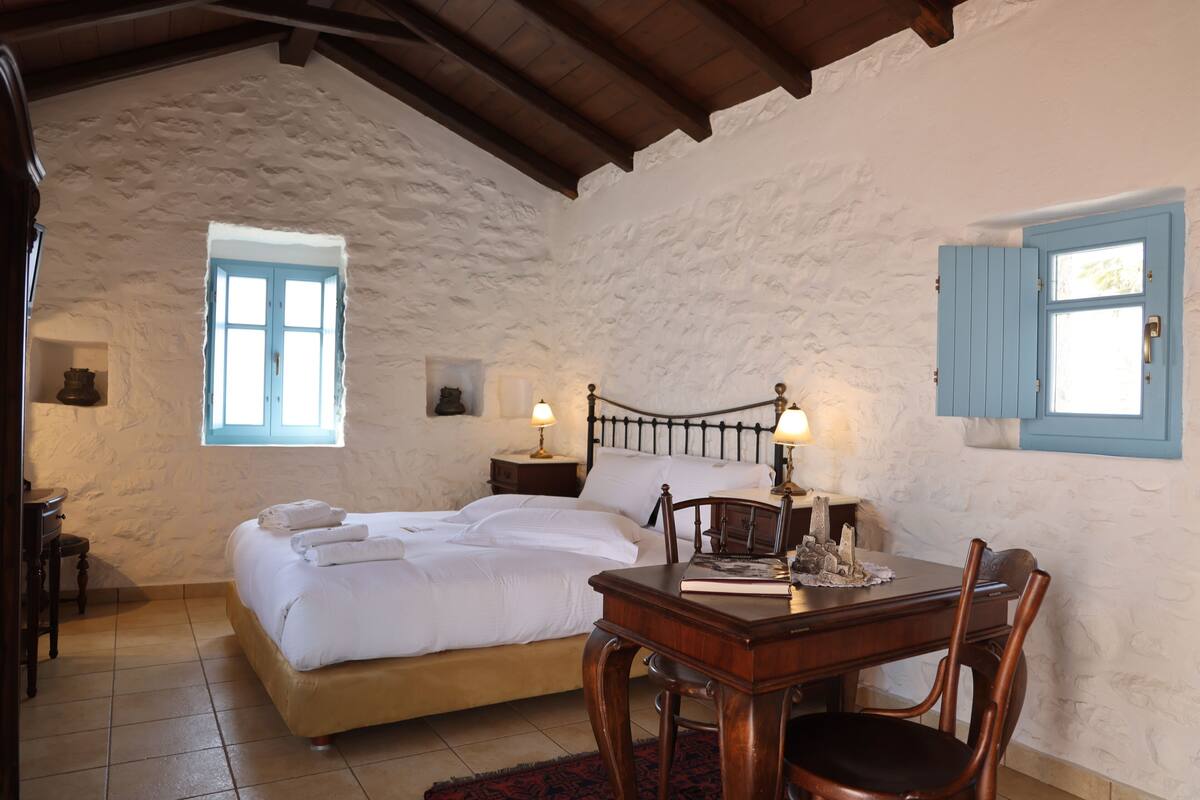 A bedroom with a bed, bedside tables, a desk, and chairs.