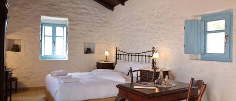 A bedroom with a bed, bedside tables, a desk, and chairs.