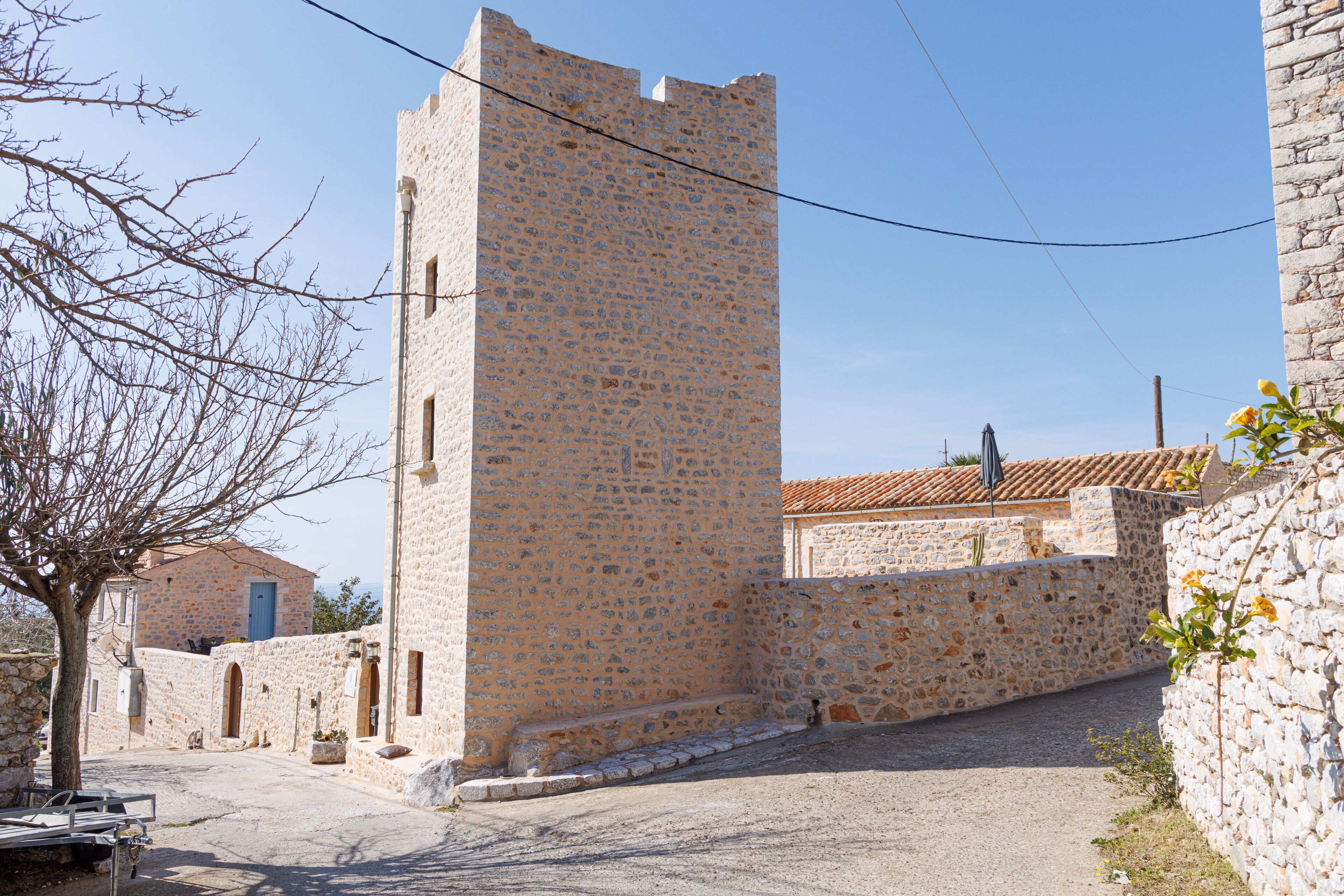 Une tour de pierre surmontée de créneaux, une rue pavée et un bâtiment doté d’un toit en tuiles.