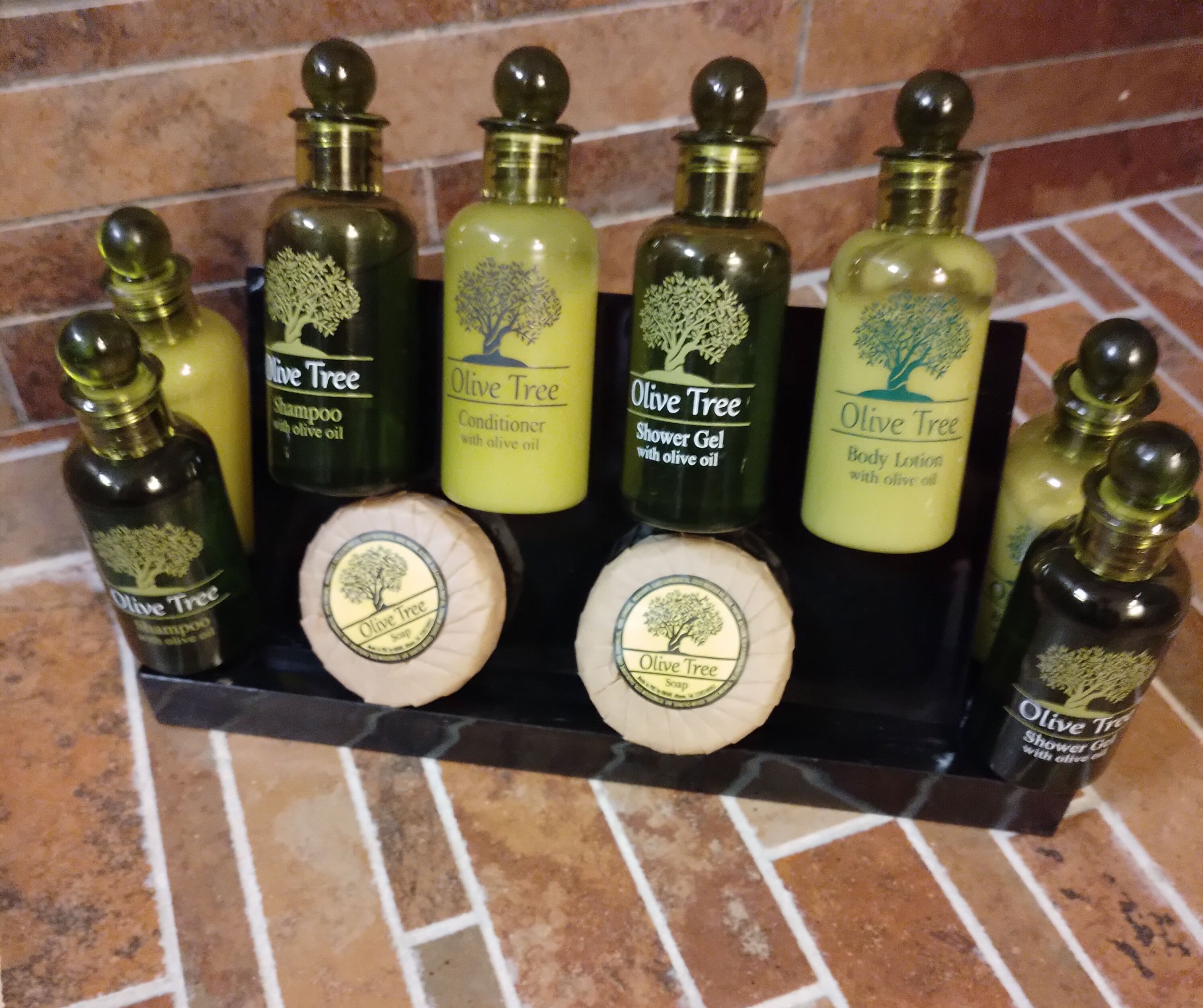 Présentation d’une gamme de produits Olive Tree, comprenant du shampooing, de l’après-shampooing, du gel douche, du lait pour le corps et du savon.