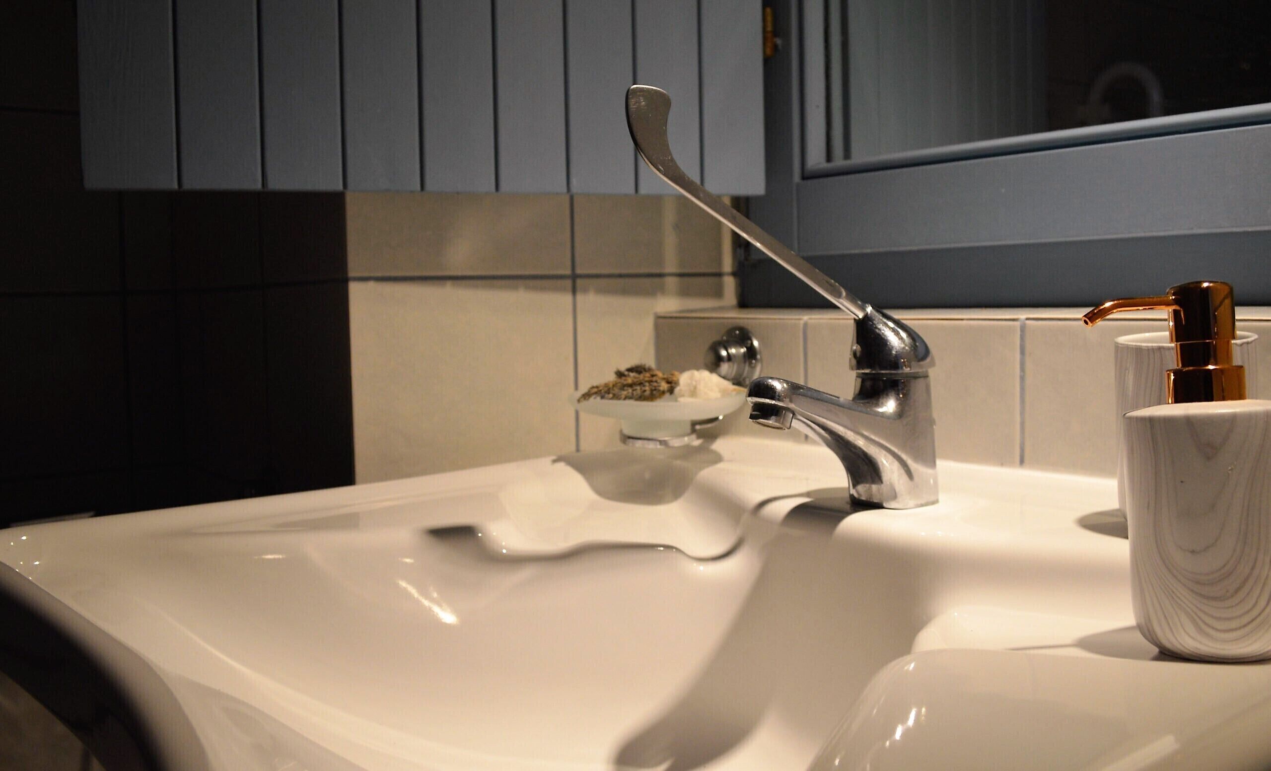 A bathroom sink with a modern faucet, a soap dish, and a soap dispenser.
