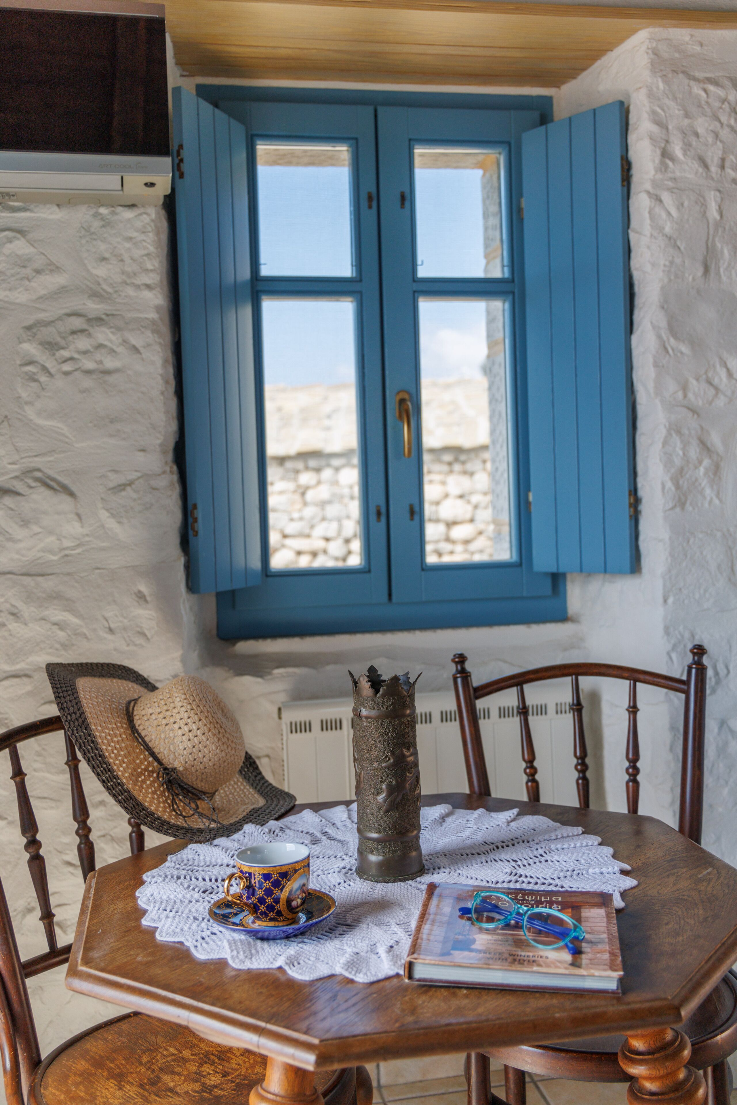 A wooden table with a lace tablecloth, a book, a pair of glasses, and a decorative vase.